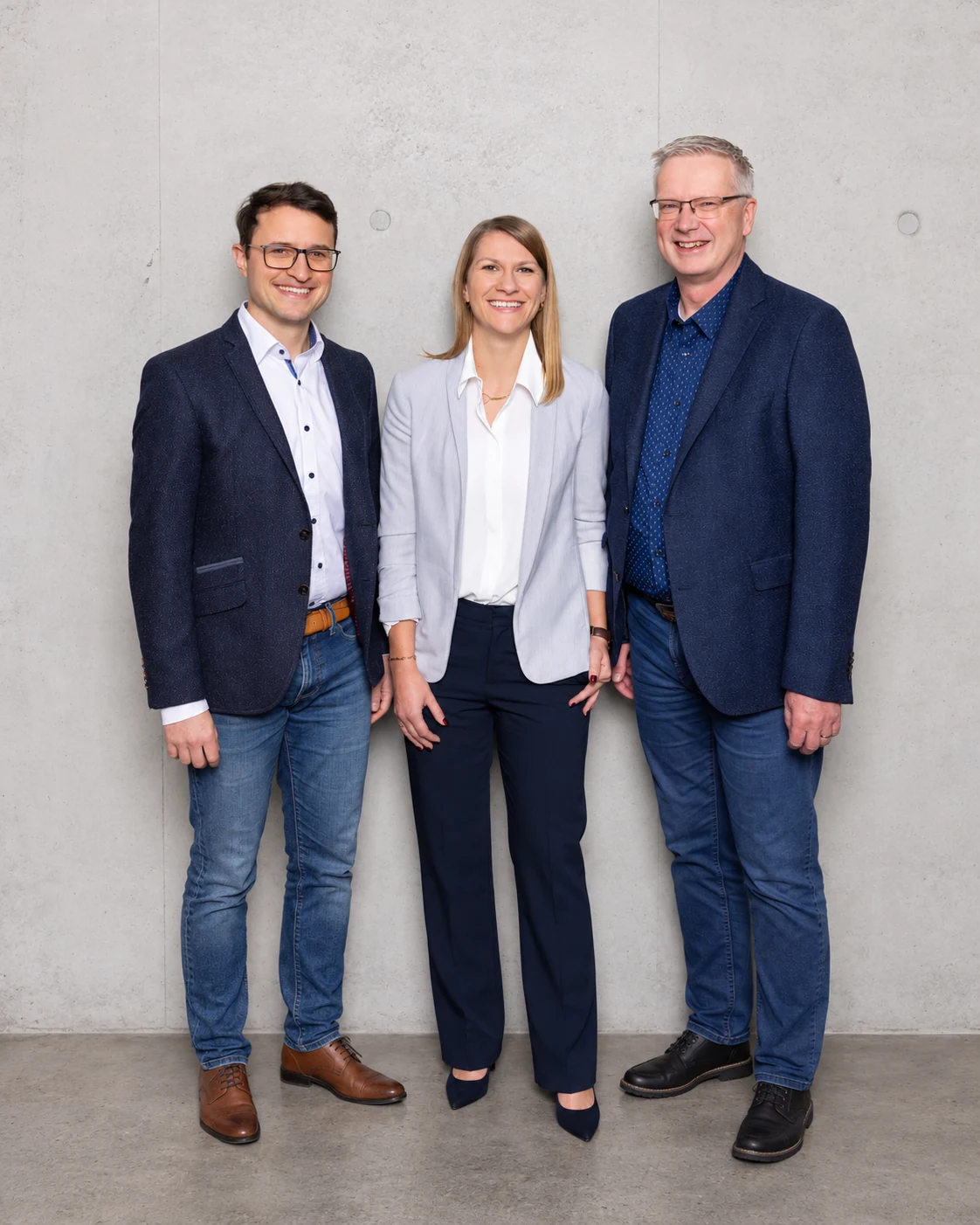 Drei Teammitglieder vor einer Betonwand