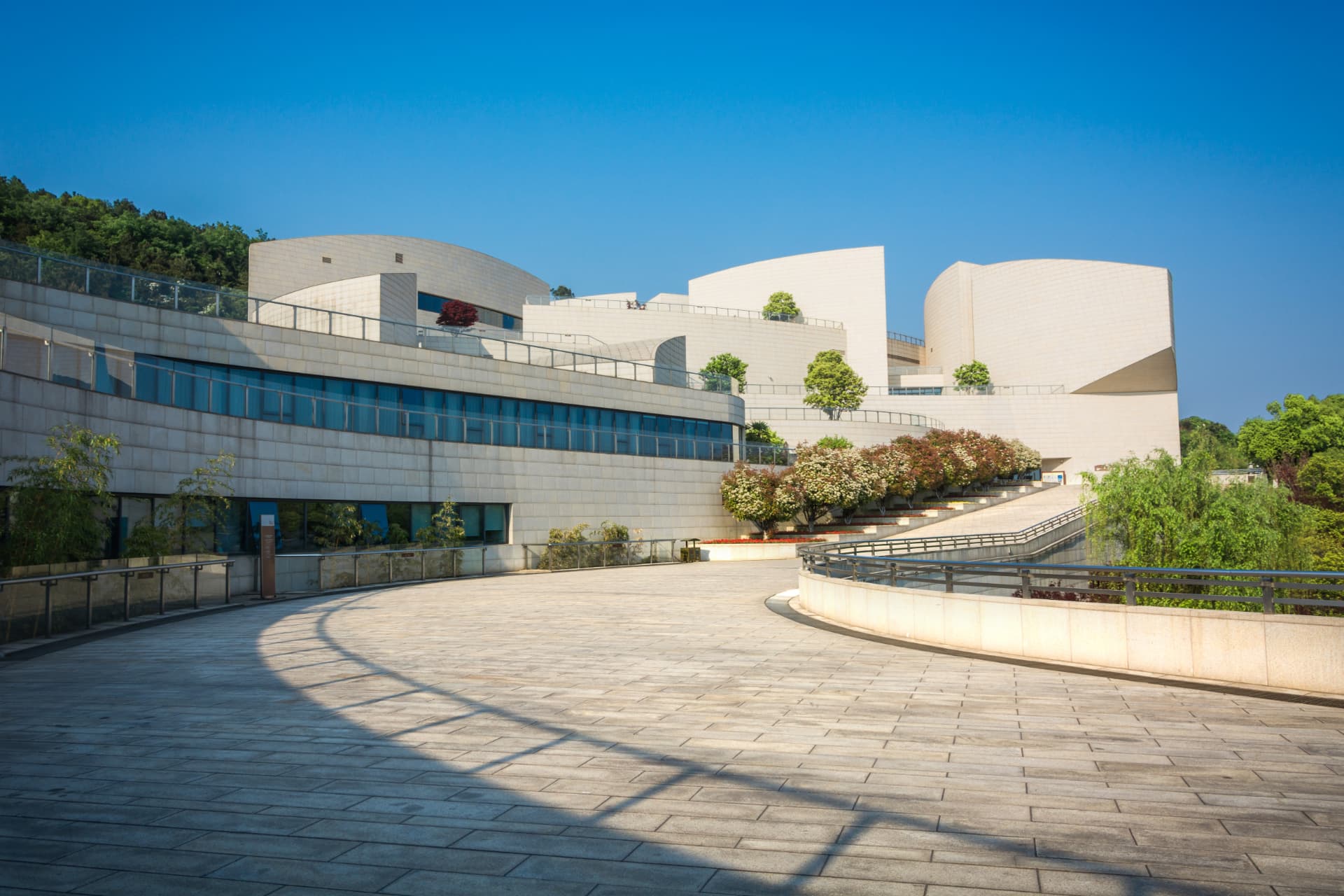 Modernes Gebäude mit geschwungener Natursteinfassade und breitem Vorplatz