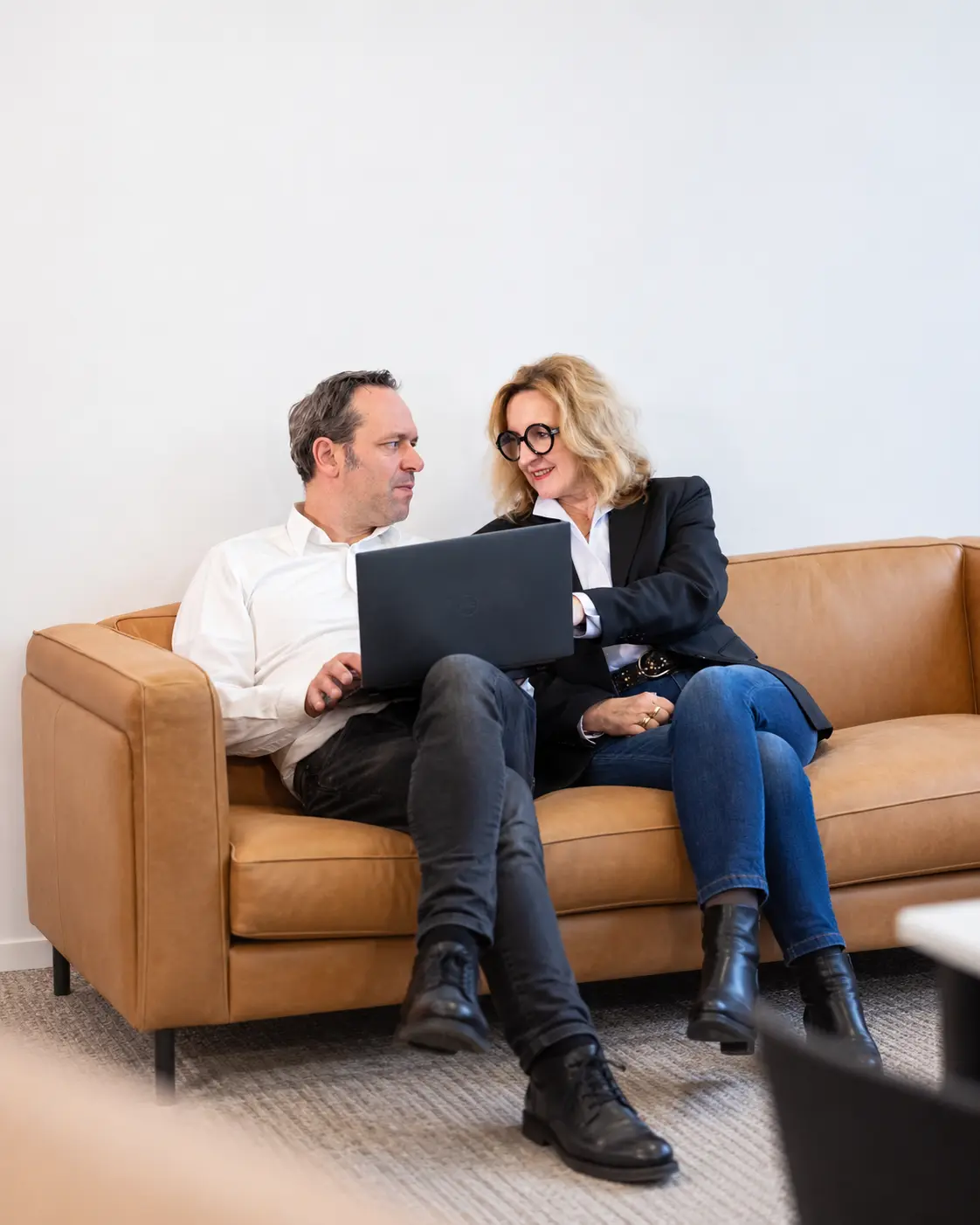 Zwei Personen betrachten gemeinsam einen Laptop auf einem Sofa