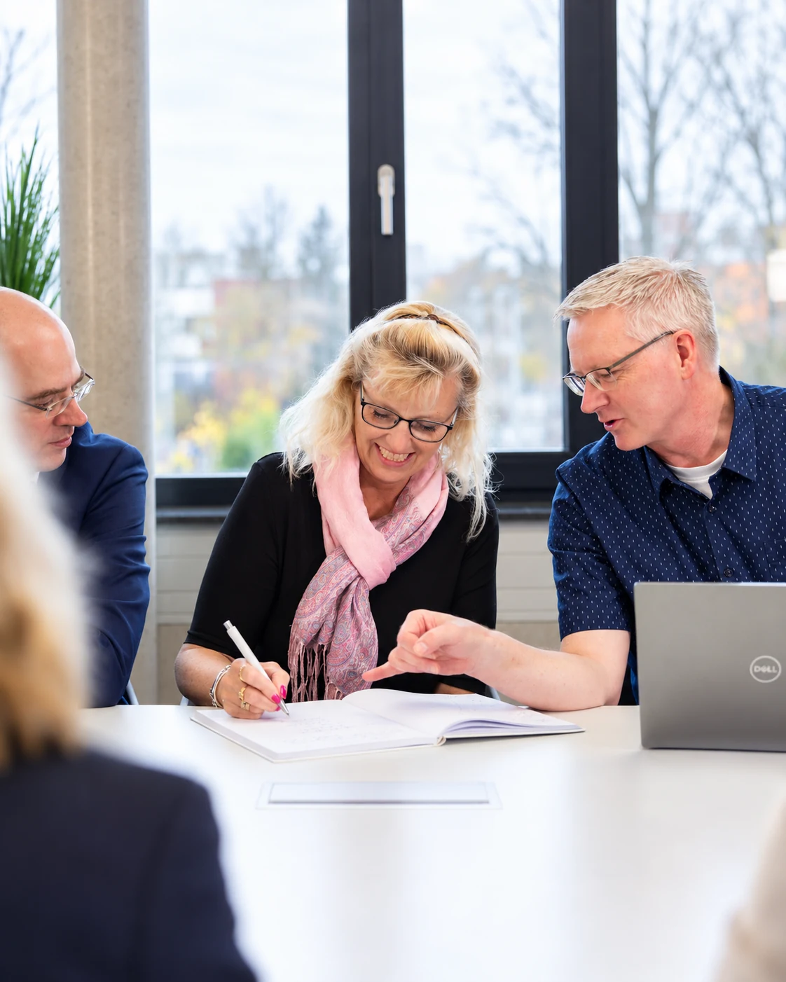 Drei Personen arbeiten gemeinsam an Unterlagen am Tisch